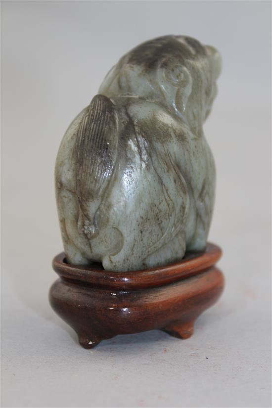 A Chinese pale grey and black jade carving of a lion-dog, Ming dynasty, 6cm., wood stand